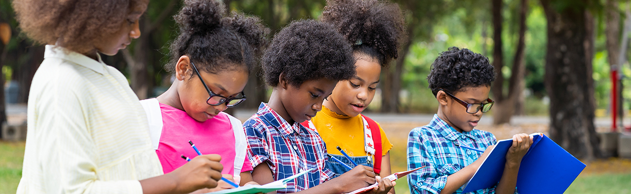 H-group-elementary-students-taking-notes-in-notebooks-outdoors.jpg